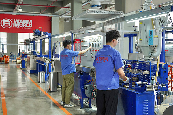 工人在操作電伴熱帶護(hù)套擠出設(shè)備。 環(huán)瑞電熱供圖